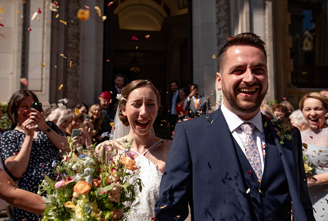 Natural wedding photography of couple laughing during confetti throw in Bristol